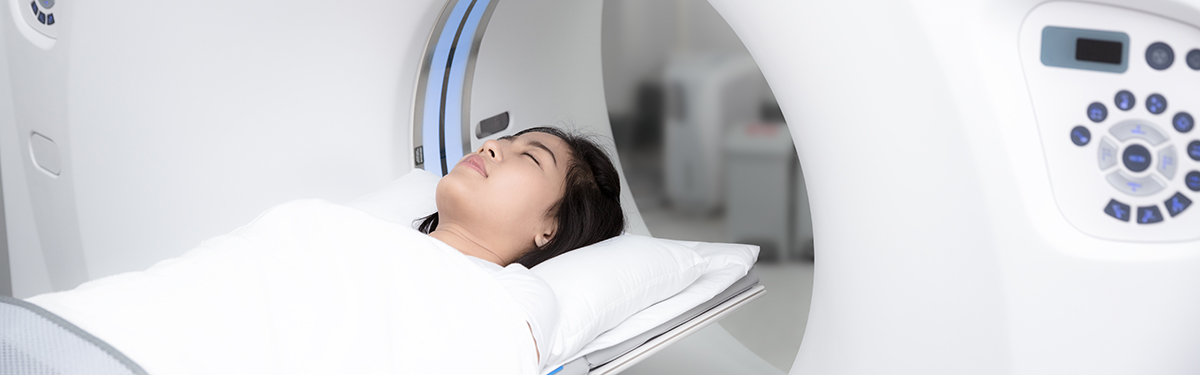 Asian lady sleep on a CT Scan bed and panel control by Radiologic technician